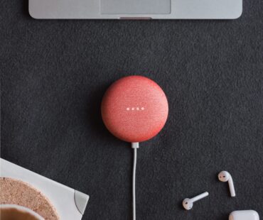 flat lay photography of coral Google Home Mini on black surface beside Apple AirPods