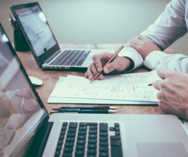 person holding a pencil near laptop