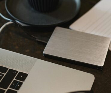 Free Closeup of an external hard drive connected to a laptop with a USB cable on a desk. Stock Photo