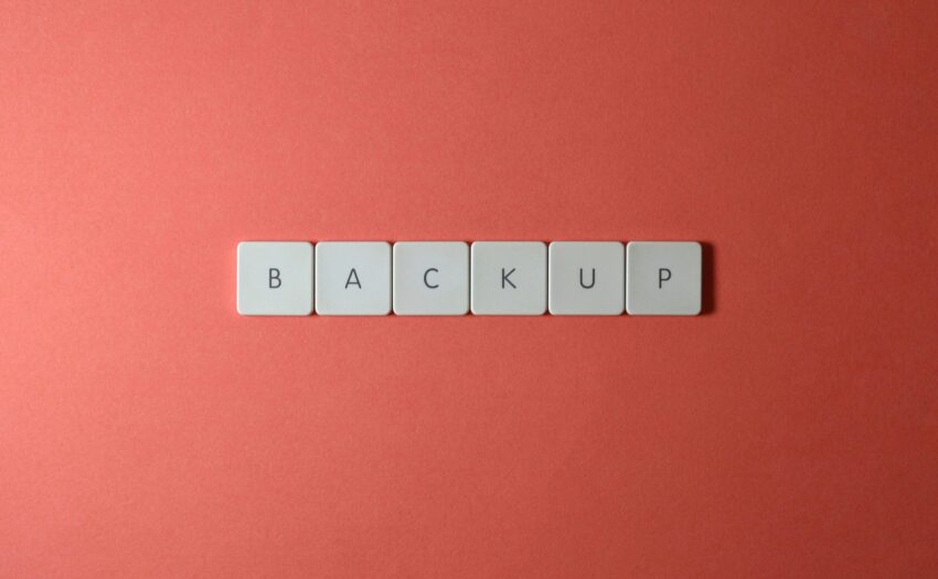 Free Close-up of keyboard keys spelling 'BACKUP' placed on a coral-colored surface. Stock Photo